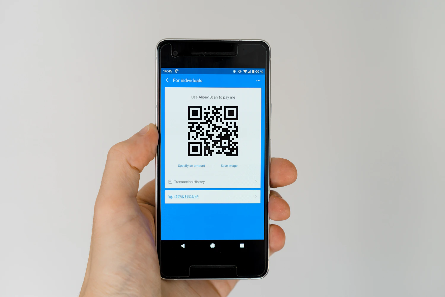 A hand holding a smartphone displaying a QR code.