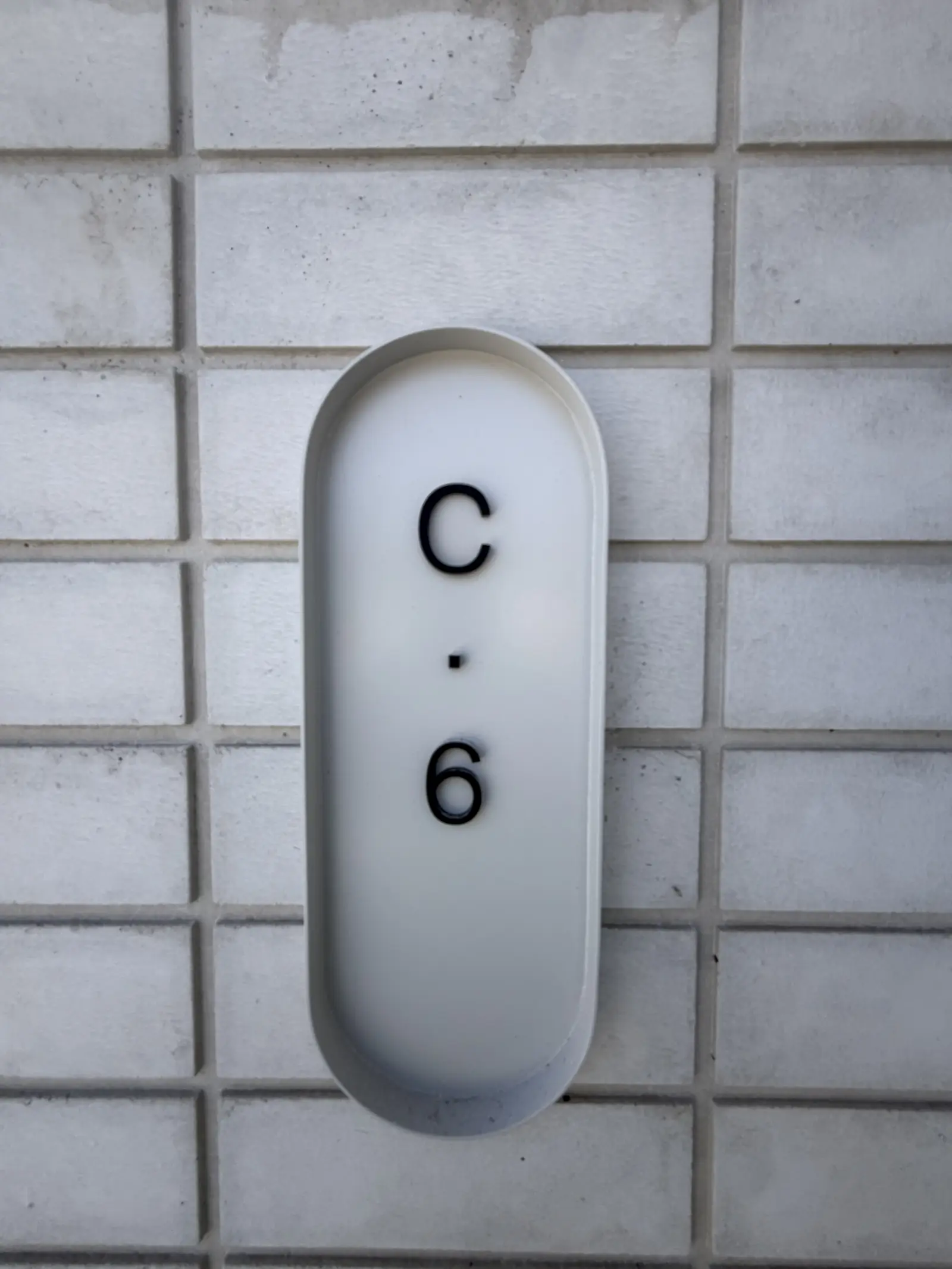 Close-up of the white tiled wall with the C 6 unit number marker, Agile IT's specific address
