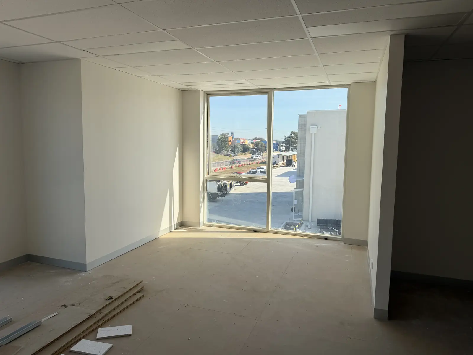 Empty interior office room with full-height window installed and trees visible beyond