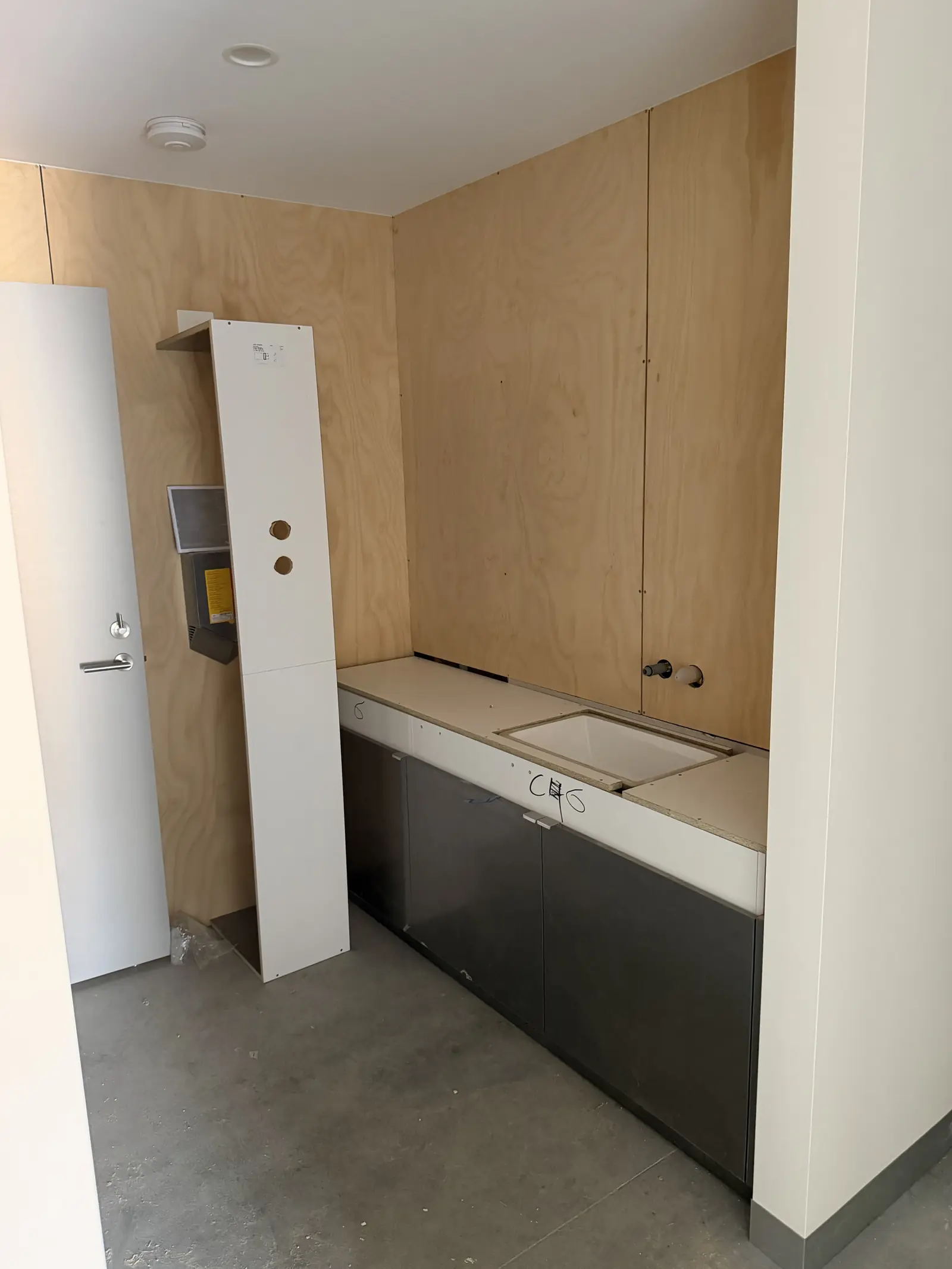 Interior fit-out detail, plywood wall panels, white counter, stainless steel mixer tap