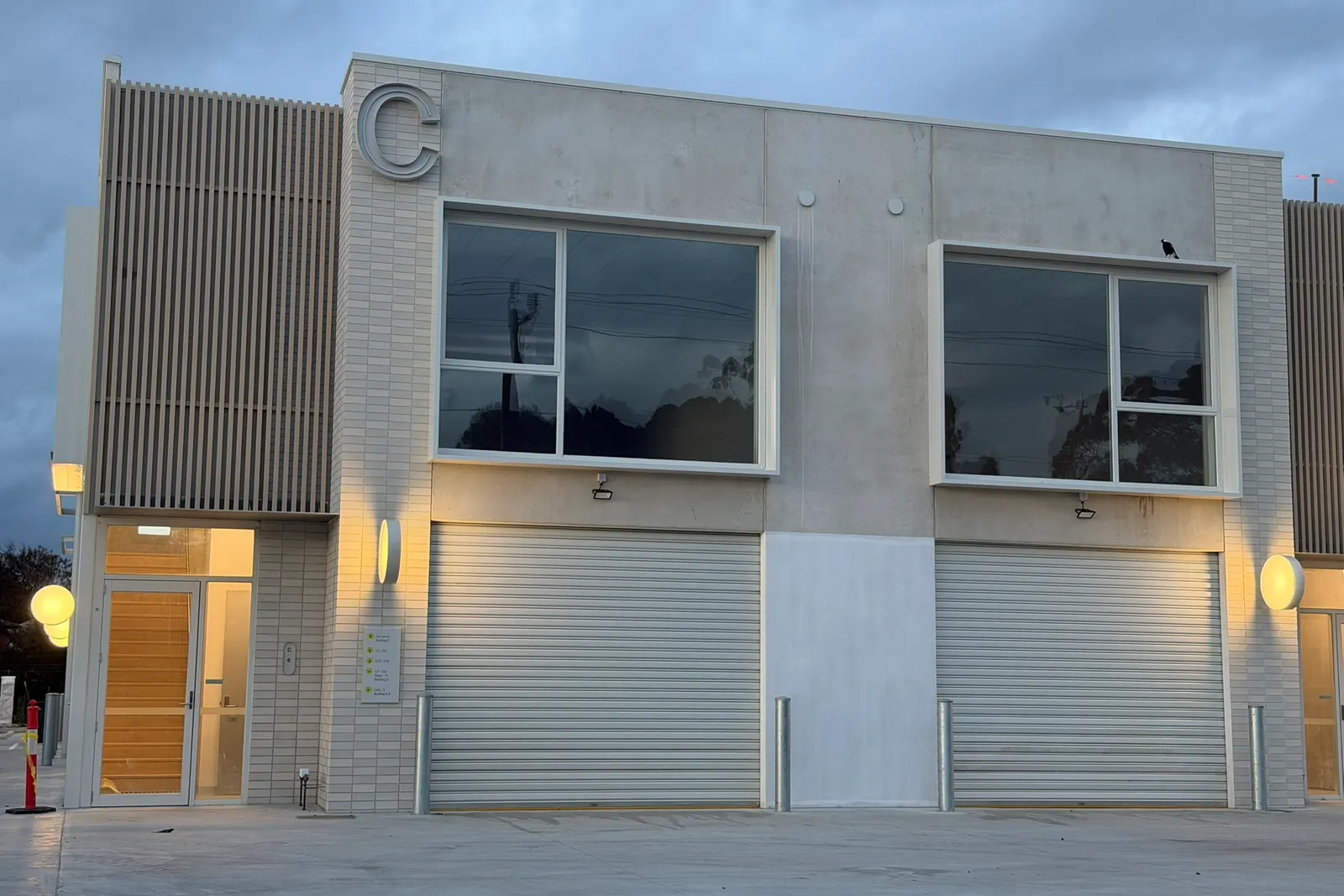 Building C at Free Form, Mornington at dusk, entry lit, white brick and concrete with timber slat features, the new home of Agile IT