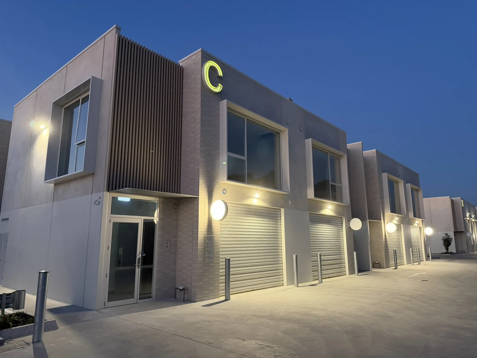 Building C at Free Form, Mornington lit up at dusk, the C sign glowing above the C6 entrance.