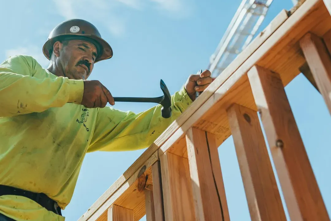 A builder fixing the top plate of a timber wall frame, for the structural work that stops problems before anyone moves in