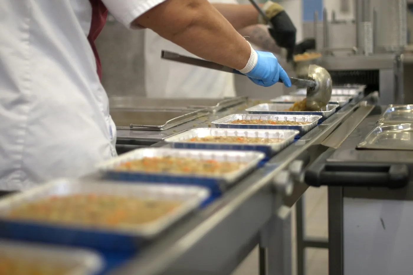 A worker filling trays of food on a production line