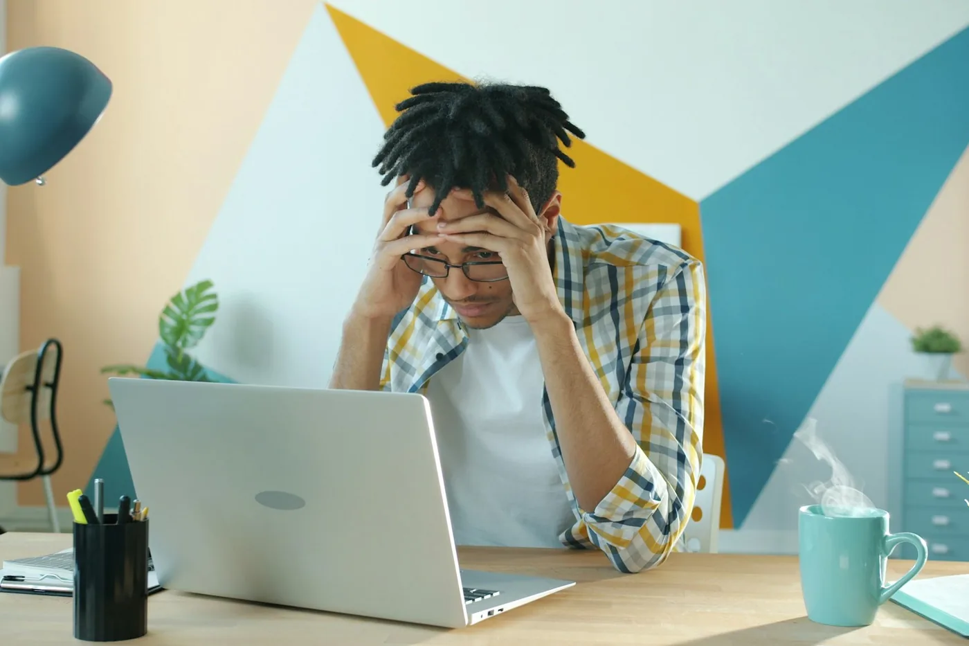 A worried man sitting at his desk with both hands on his head, looking at his laptop. Running an unsupported operating system is a quietly building problem most businesses do not see until it is too late.