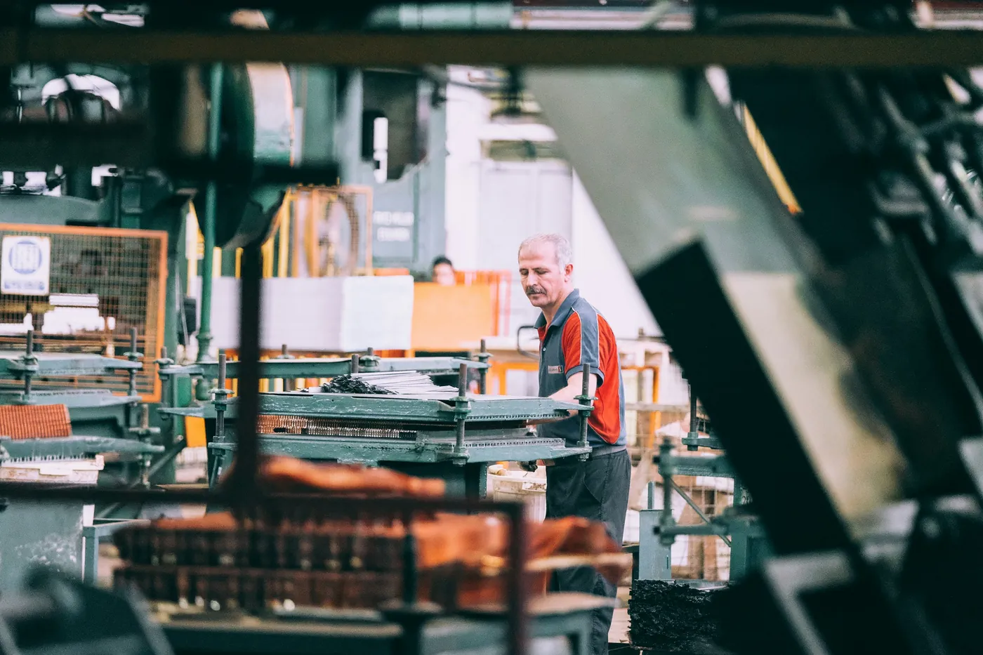 A machinist working at industrial equipment on a factory floor