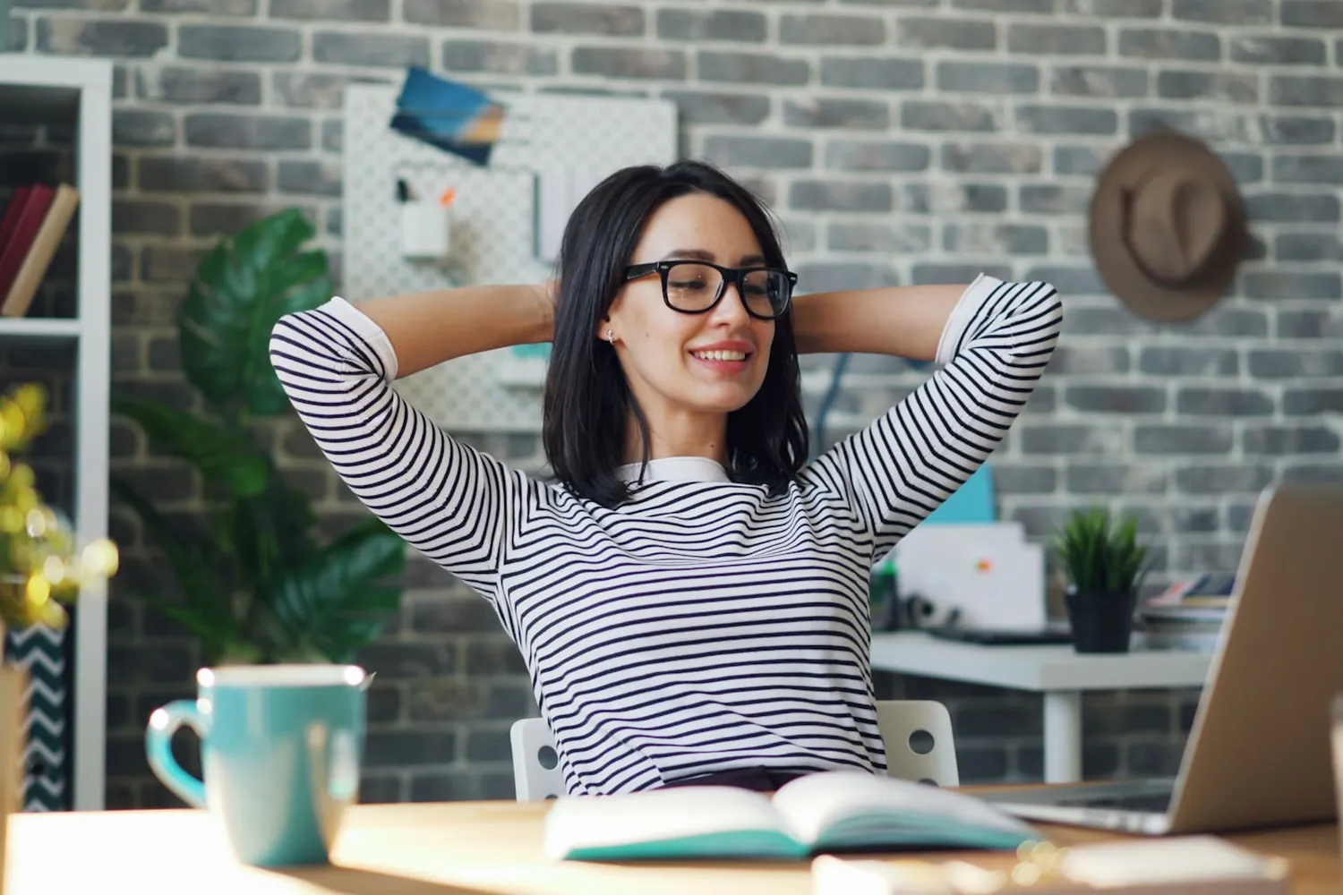 A person relaxed and smiling at their desk with a well-set-up laptop, Agile IT supplies and manages business computers as part of AgileMANAGED.