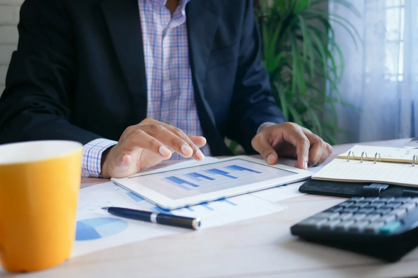 A person in business attire reviewing financial charts on a tablet at a desk, signalling a careful look at recurring service costs.