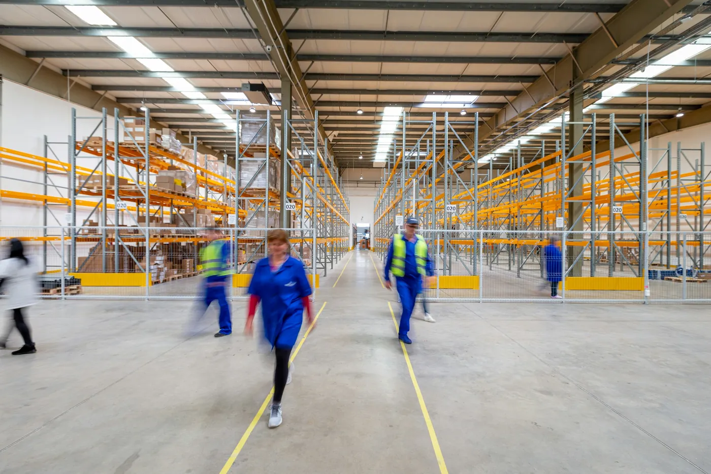 Two workers walking a racked aisle in a distribution warehouse